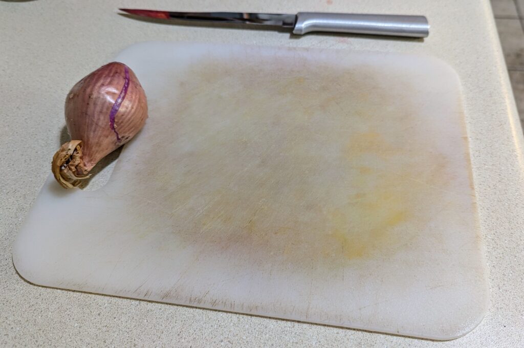 A shallot on a cutting board with a knife