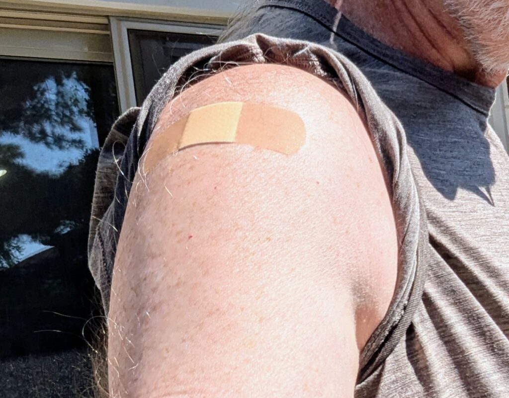 My upper right arm with a bandaid over the injection site of my pnumonia immunization