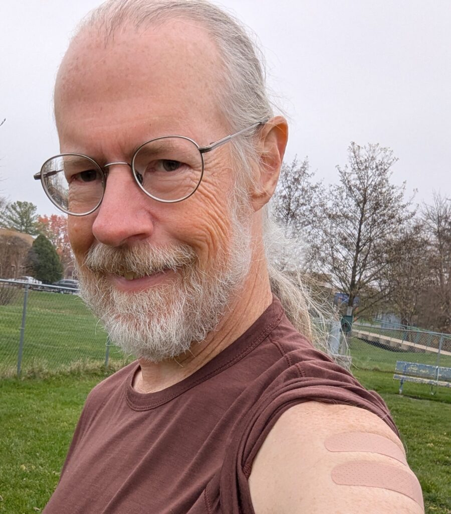 Me with two band aids on my left arm, where I got a Covid shot and a flu shot