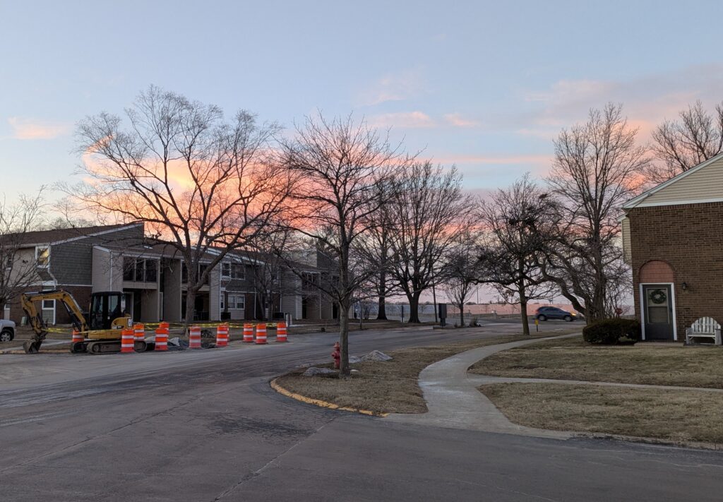 Clouds turned orange by the sunset, over orange traffic-control barrels of nearly the same color