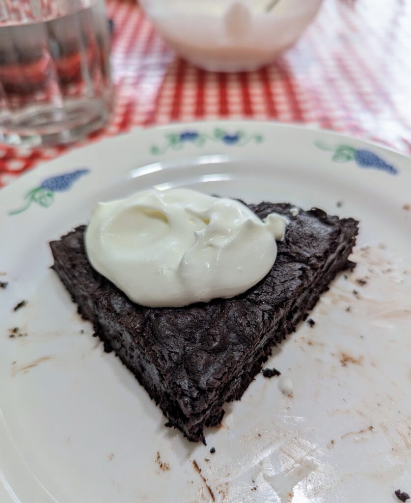 A slice of flourless chocolate cake with whipped cream on top