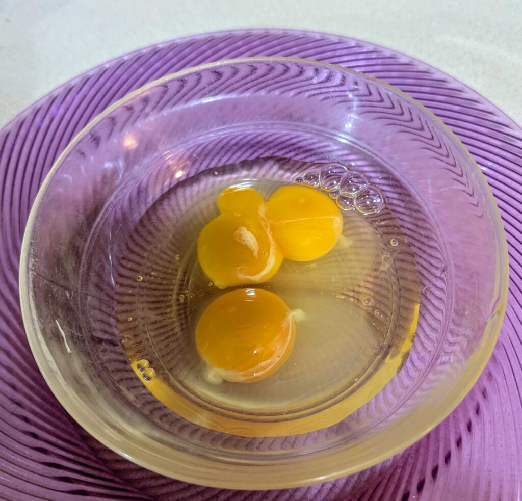 A mixing bowl with two eggs, one of them double-yoked